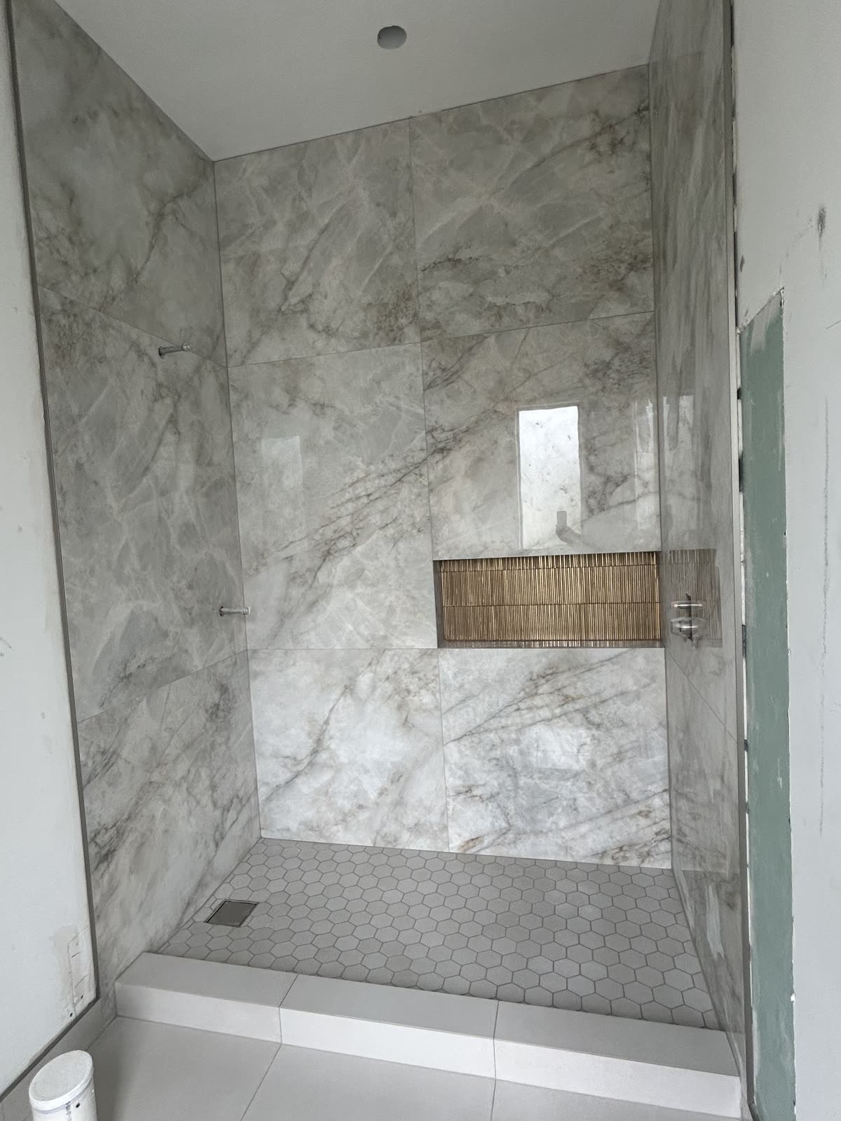 Walk-in shower with large-format tile walls, mosaic niche and hexagon mosaic shower floor